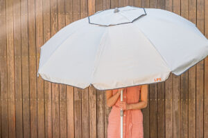 Silver LiFE Umbrella being held against a wooden fence